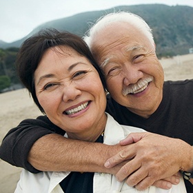  Senior couple with implant dentures in Goode, VA hugging on beach
