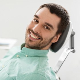 A smiling man sitting in a chair at a dental clinic